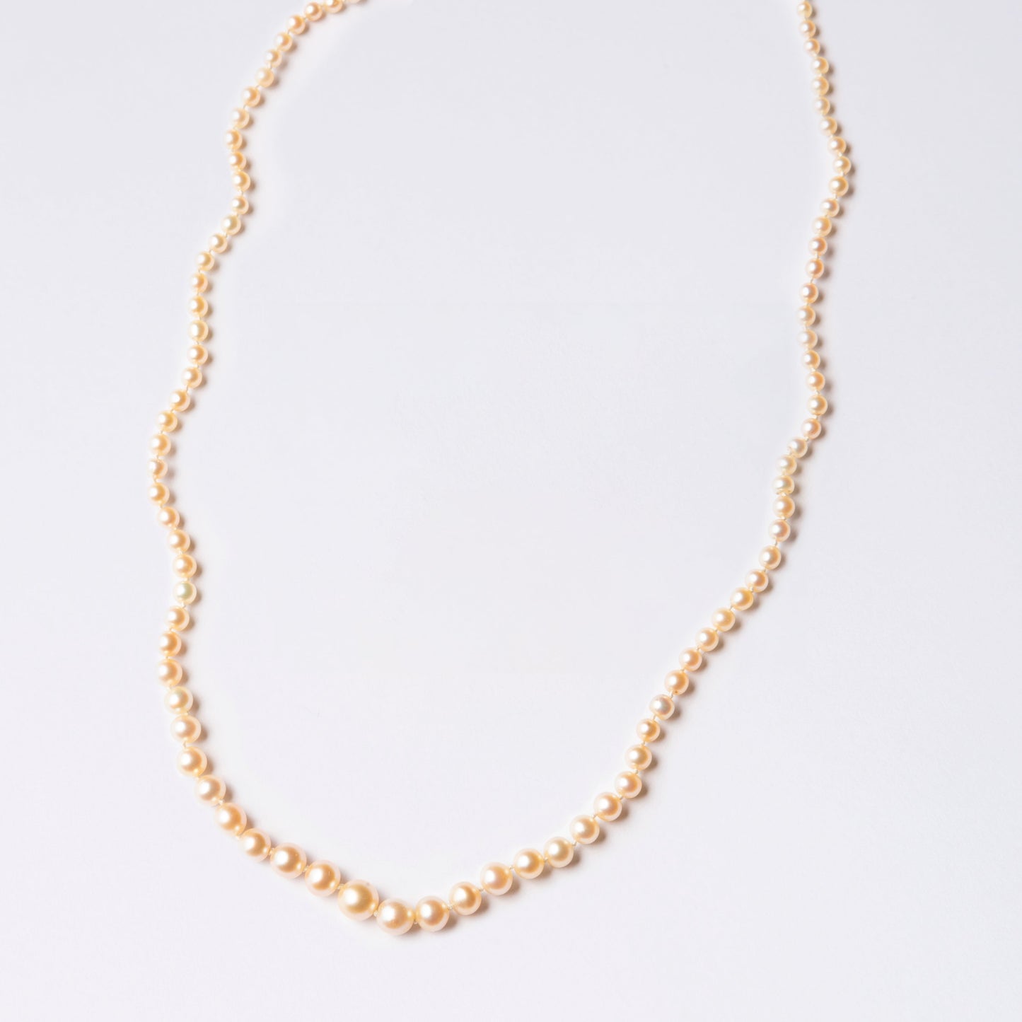 Peach-colored pearl necklace NP1 displayed on a jewelry stand