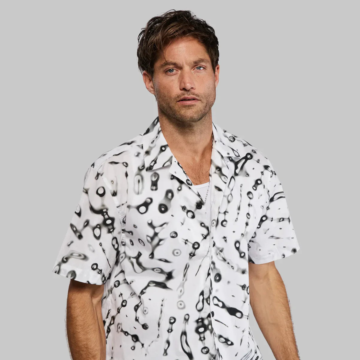 White and black abstract patterned short sleeve shirt with button down collar perfect for sports and fitness activities