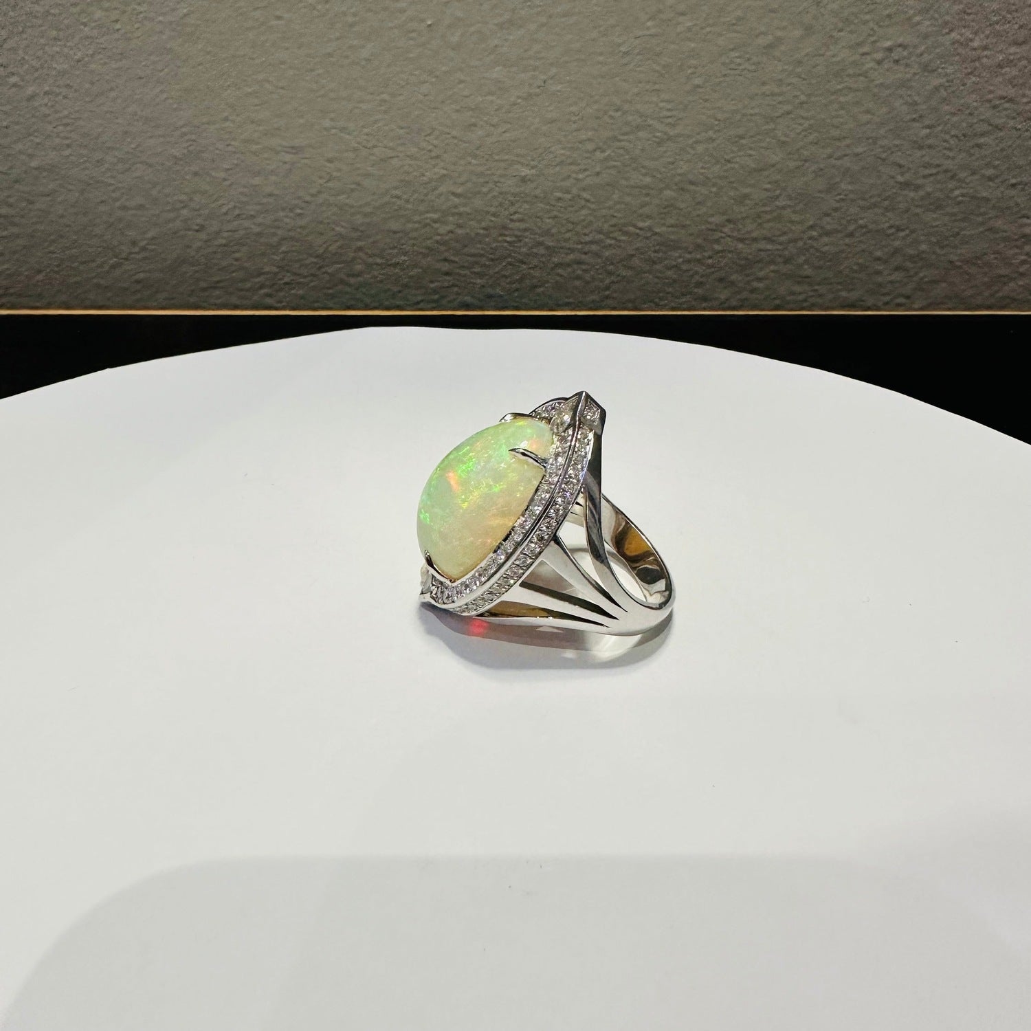 Opal ring with diamond accents on a silver band displayed near a Red Nike Baseball Cap