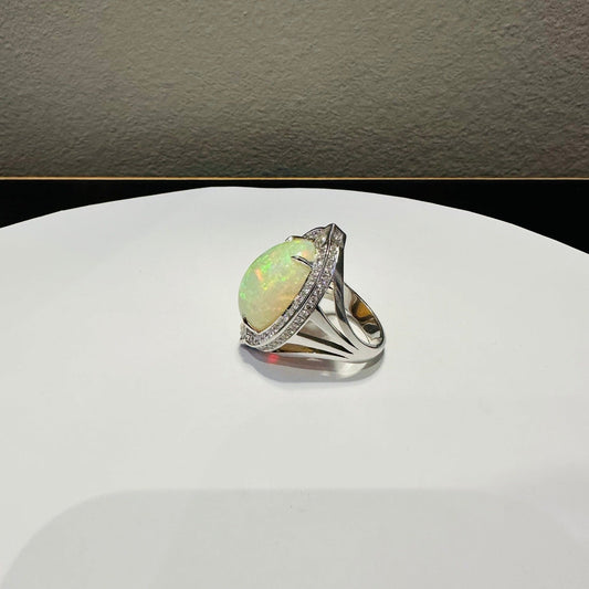 Opal ring with diamond accents on a silver band displayed near a Red Nike Baseball Cap
