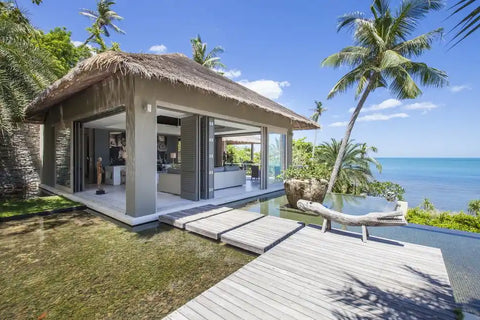 Modern beachside bungalow with thatched roof and wooden deck for PRODUCTS sale and use