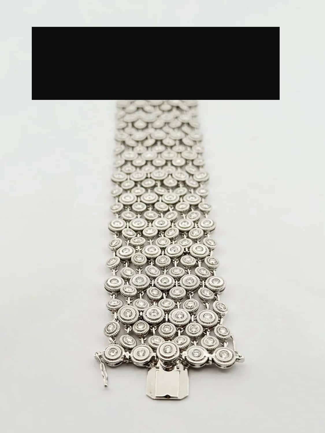 Silver-toned multi-row bracelet featuring a mesh of circular links with embedded clear stones and an ornate rectangular clasp