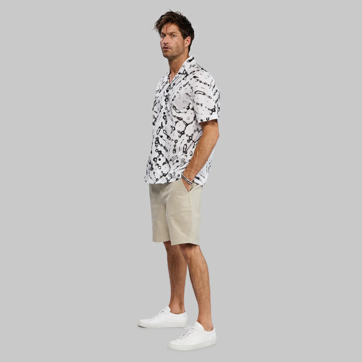White skull patterned button-down shirt paired with khaki shorts and white sneakers