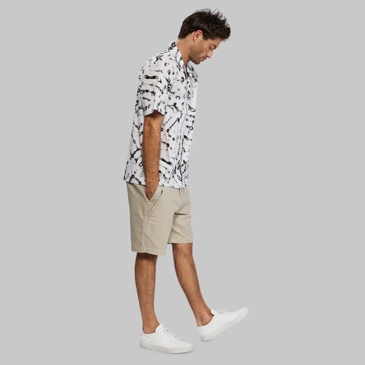 White and black tie-dye short-sleeve button-down shirt with khaki shorts and white sneakers