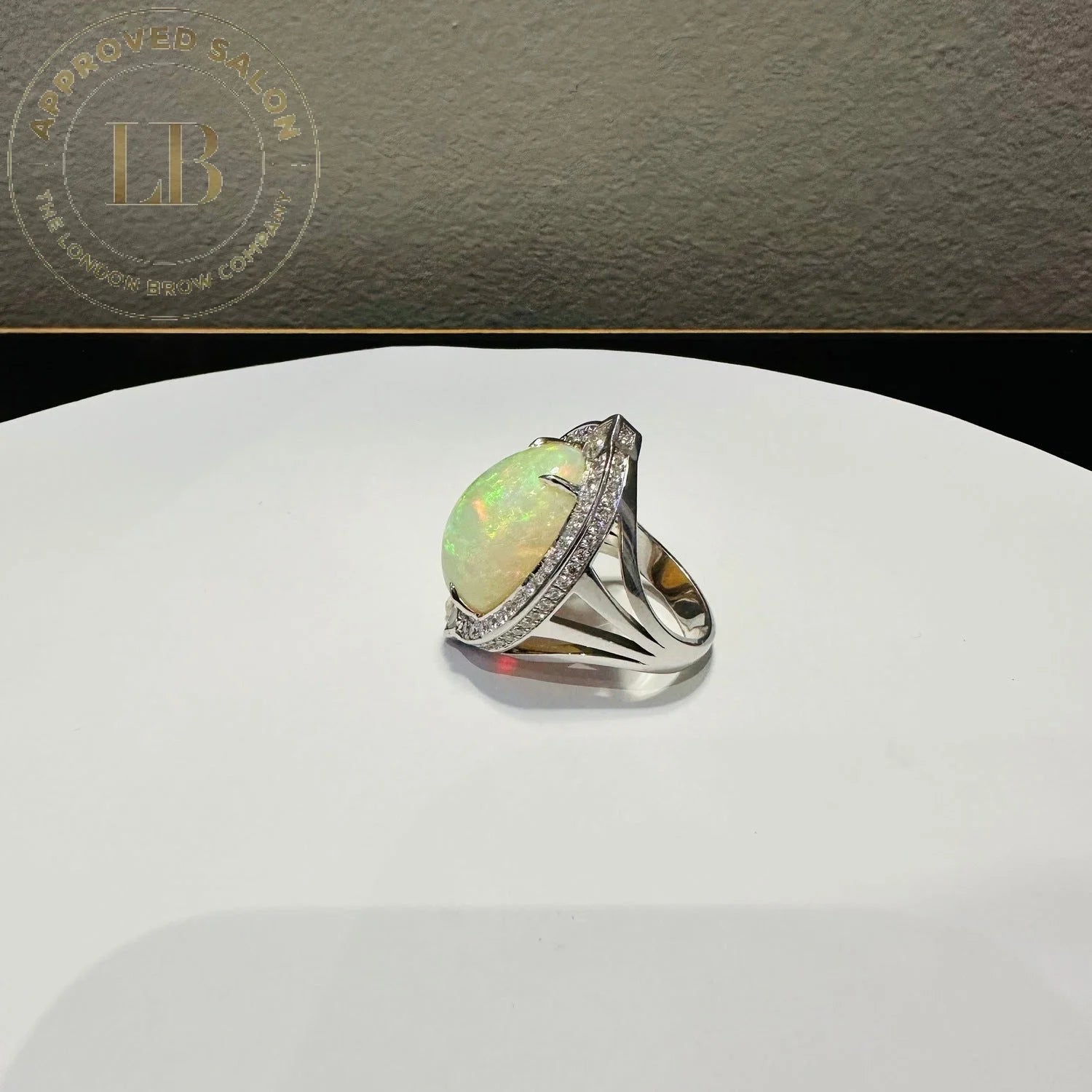 Opal ring with diamond accents on a silver band displayed near a Red Nike Baseball Cap