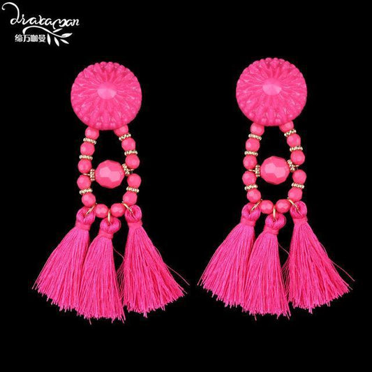 Vibrant fuchsia tassel earrings with floral bead and gold accents